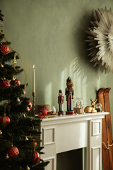 Close-up of Christmas decorations on a fireplace — nutcracker, candle, Christmas tree, snow globe and small wrapped gifts creating festive charm.