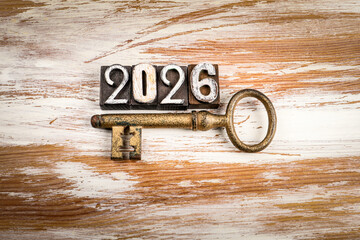 2026 made from vintage wooden letterpress blocks with antique metal key on rustic wooden background symbolizing New Year Goals opportunities and success concept
