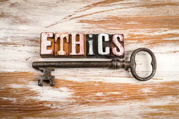 Word ethics made from vintage wooden letterpress blocks with antique metal key on rustic wooden...
