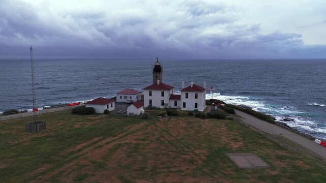 Aerial view of Beavertail Lighthouse in Beavertail State Park at the entrance to Narragansett Bay on Conanicut Island. The camera dolly in and boom up to the lighthouse on a cloudy day.
