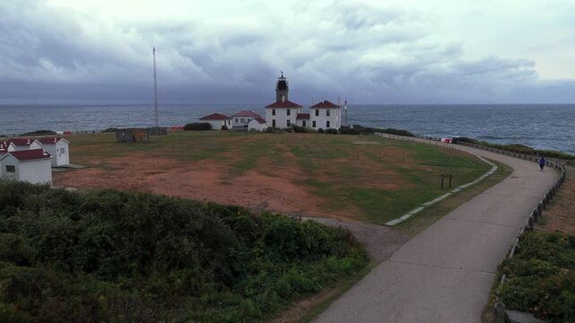 Aerial view of Beavertail Lighthouse in Beavertail State Park at the entrance to Narragansett Bay on Conanicut Island. The camera dolly in and boom up towards the lighthouse on a cloudy day.