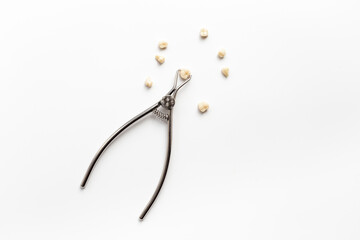 Many human teeth crown for dental implantation with tooth extraction forceps on white background. Professional Dentist tools, top view