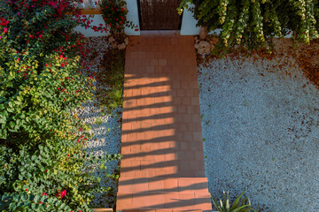 Terracotta garden path surrounded by green plants and flowers mediterranean spain