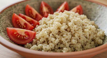 Close up of quinoa and sliced tomatoes in a rustic ceramic bowl