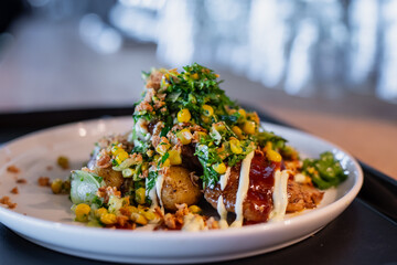 Modern restaurant dish featuring roasted potatoes topped with creamy sauce, herbs, crushed nuts, and corn garnish, representing fine dining creativity and detailed gourmet presentation