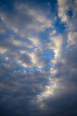 Bright blue sky partially covered with soft clouds glowing with golden light, showing serene beauty of evening weather and calm natural contrast between illumination and atmospheric movement