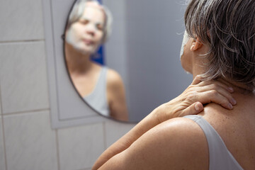 A woman performs cosmetic procedures in front of a mirror