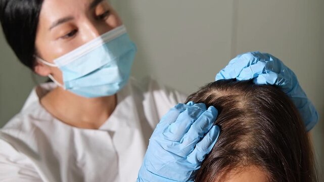 Examination of the scalp and hair by an asian trichologist doctor