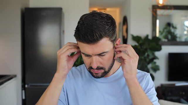 Stressed out man using ear plugs to stop the noise 