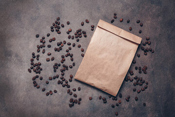 Blank brown paper bag mockup and roasted coffee beans flat lay on dark rustic background, top view, brown craft packaging