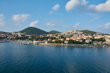 Fototapeta premium Panoramic view of Gruz harbor in Dubrovnik, Croatia, with boats and yachts in the marina and the city spreading over green hills under a blue sky.