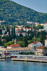 Obraz premium A lone motorboat navigates the calm blue waters of the Adriatic Sea, with the picturesque coastline of Dubrovnik and its hills in the background.