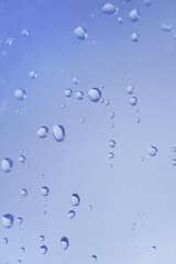 水滴の付いた窓ガラス　透明感のある抽象的な青い背景　湿度　結露　雨粒