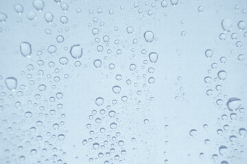 水滴の付いた窓ガラス　透明感のある抽象的な青白い背景　湿度　結露　雨粒
