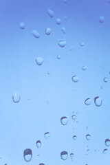 水滴の付いた窓ガラス　透明感のある抽象的な青い背景　湿度　結露　雨粒