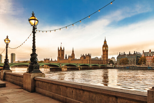 Palace of Westminster and Big Ben viewed from the South Bank with historic lamps and string lights over River Thames