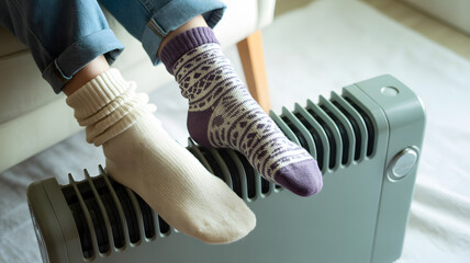 Close-up of feet in cozy winter socks resting near gray electric heater home comfort warmth and relaxation concept