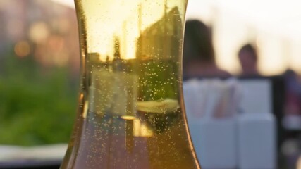 Enjoying a cold beverage while watching the sunset from a rooftop bar filled with vibrant city life.