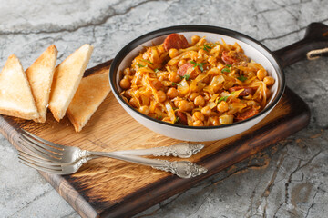 Spanish vegetable stew with cabbage, chickpeas, chorizo ​​and paprika close-up in a plate on the table. Horizontal