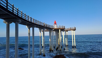 wooden seaside walkway and observatory with red roof lighthouse under blue sky