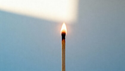 Close up of single lit wooden matchstick with flame on plain background