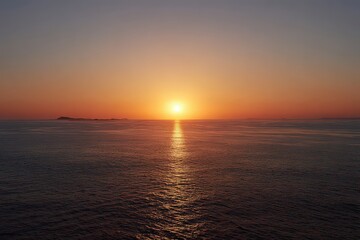 Obraz premium Sunset Over Water Surface with Golden Reflection and Orange Sky
