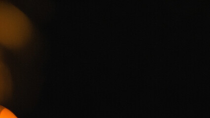 Dark cinematic background with warm amber light leaks and subtle film grain texture. Ideal for vintage photography effects, video overlays, and atmospheric digital designs.