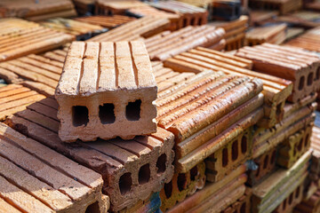 Pile of bricks for construction work, brown brick background, Close-up of stacked bricks ready to be used as a construction material.