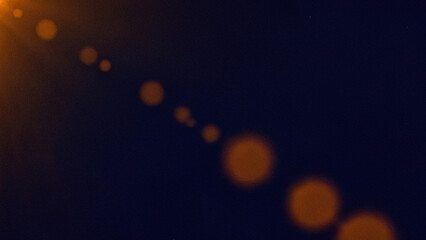 Cinematic orange lens flare light leaks on a dark blue grainy background. A vintage film texture overlay with bokeh effects, perfect for photography, video edits, and graphic design projects.