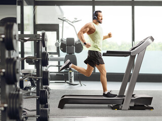 Fototapeta premium Full length shot of a man at a gym running on a treadmill