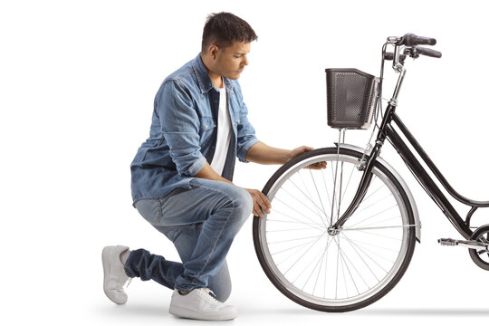 Young man kneeling and checking bicycle tire