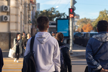 A young man waiting for the traffic light to turn green to cross the road.