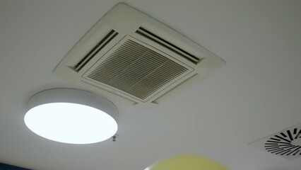Balloons floating near ceiling air conditioning unit and lights. Creative