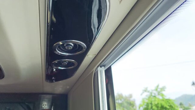 Close up of a ventilation vent on the ceiling of a moving bus.
