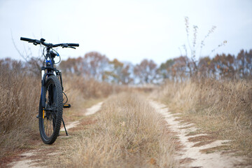 bike stands on in the field. A mountain bike stands on a field path with dry autumn grass. cycling. Mountain bike. outdoor cycling activities. active rest, sports, travel. space for text
