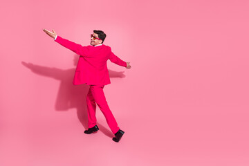 Charismatic man in a pink suit dancing cheerfully against a vibrant background, conveying joy, style, and modern elegance