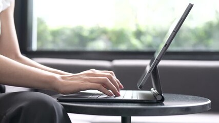 A young woman sitting in a modern café using a smartphone with a tablet on the table, working or studying in a relaxed atmosphere. - Powered by Adobe