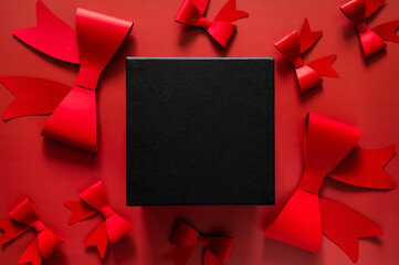 Black Friday background with large black box centerpiece surrounded by blurred red ribbons and bows on a red background for sales text.