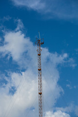 Obraz premium High steel tower with mobile phone antenna and radio equipment against a blue sky for wireless cellular communication network