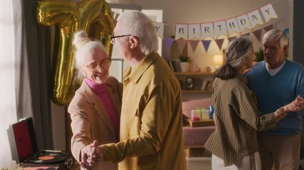 Two joyful elderly couples dancing together and speaking in cozy warmly lit living room decorated for birthday celebration - Powered by Adobe