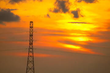 Obraz premium The sunset silhouettes of the city's power line towers and communication antennas against a golden sky, reflecting industrial technology and construction.