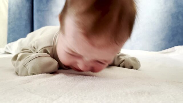 A small newborn baby lies on its stomach and tries to raise its head. Concept of healthy development of baby 0-6 months, baby care.