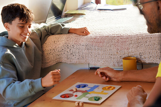 Van life, family trips and vacations. preteen boy playing Parcheesi in a camper van.