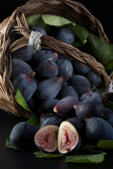Fichi maturi in un cesto di vimini su sfondo nero
