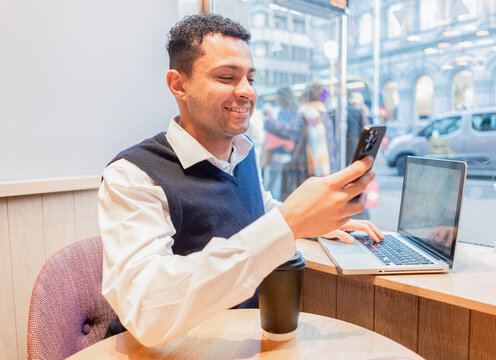 A young, elegant executive of mixed ethnicity smiles, holding a mobile phone in historic Dublin.