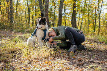 Photographer and hiker woman enjoying walking her dog off-leash in an autumn forest. 