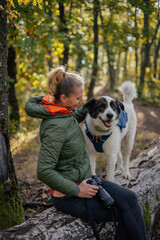 Photographer and hiker woman enjoying walking her dog off-leash in an autumn forest. 