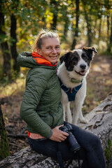 Photographer and hiker woman enjoying walking her dog off-leash in an autumn forest. 