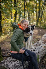 Photographer and hiker woman enjoying walking her dog off-leash in an autumn forest. 