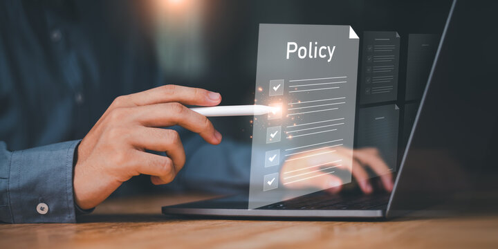 Businessman using digital pen to interact with virtual policy document on laptop screen, symbolizing digital transformation, compliance, policy implementation, governance, business standardization.